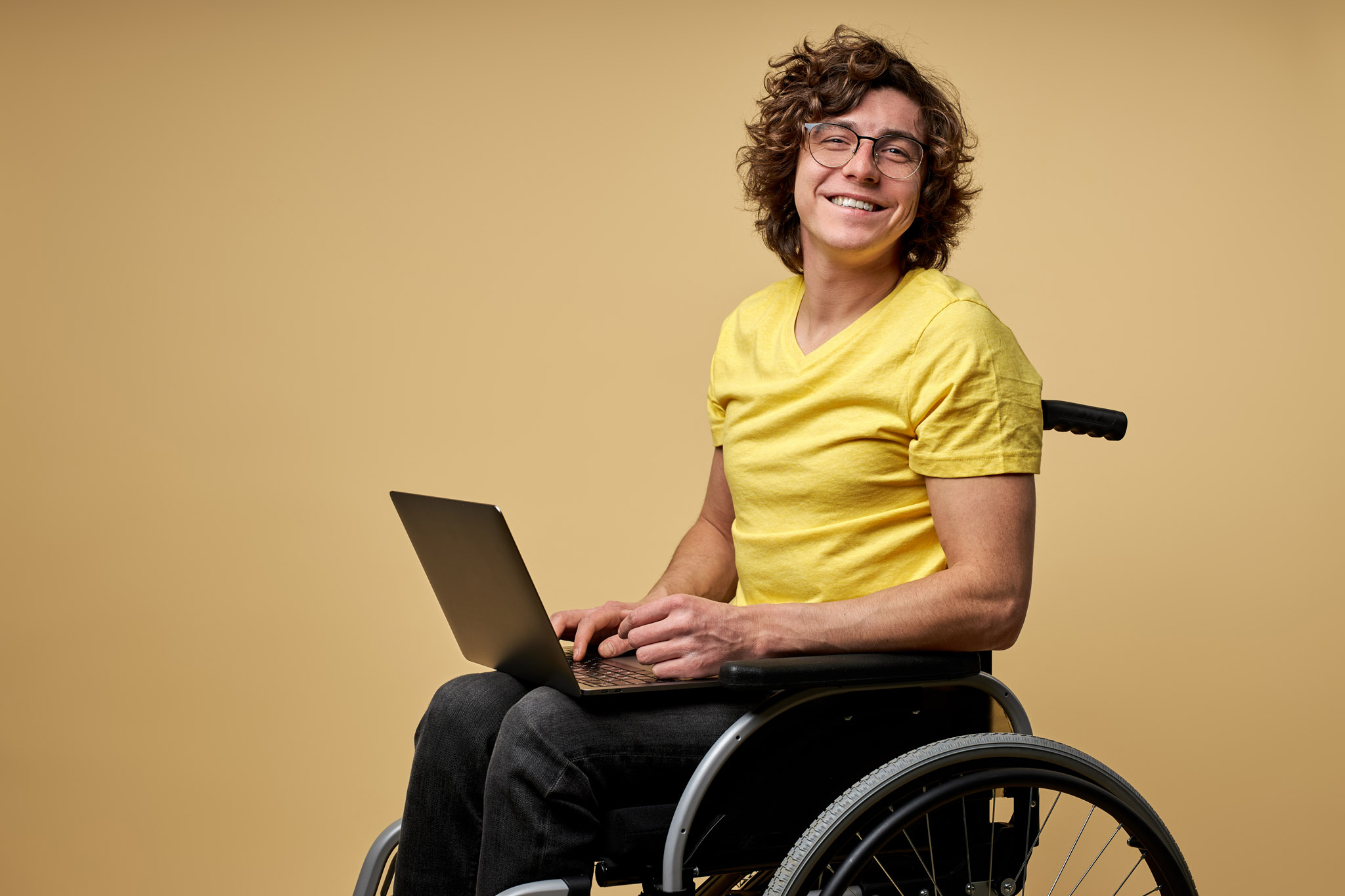 Disabled man sits in a wheelchair with laptop, working online